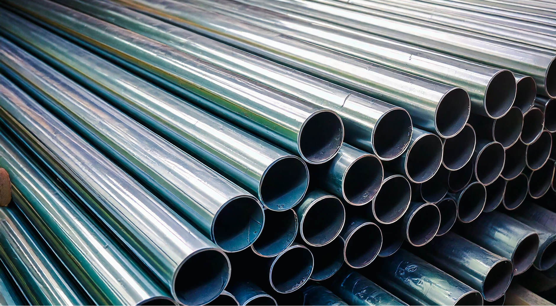 Stack of shiny metal pipes with visible round openings, stacked diagonally.
